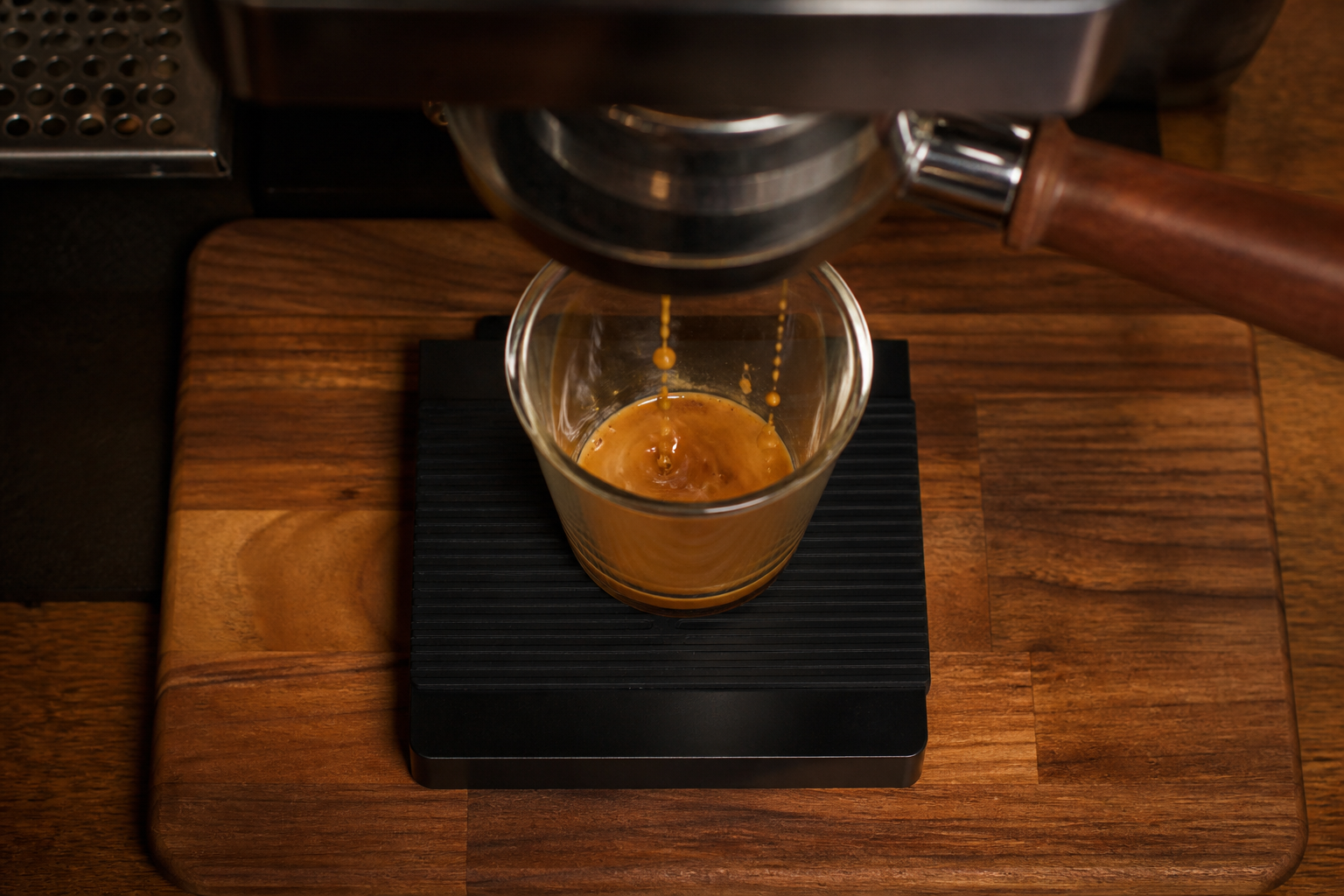 Espresso beginning to flow from a portafilter into a glass cup on a scale